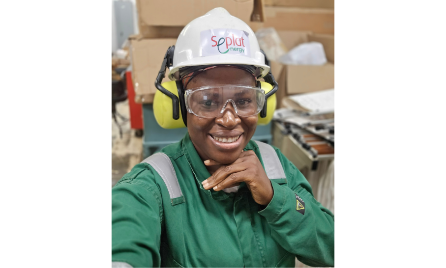 A photo of ECT student Calista smiling to camera wearing a hardhat and green overalls