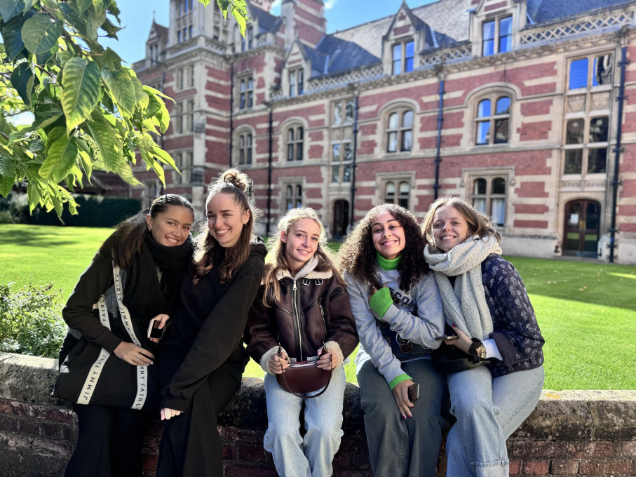 Students seated on a wall in front of a large building