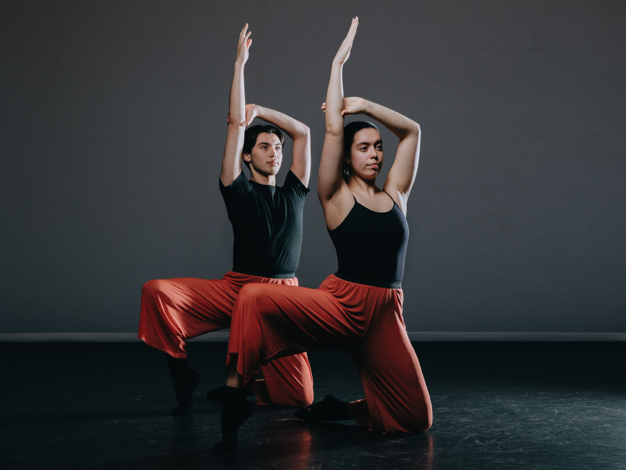 Male and female dancer holding poses in black vests and red trousers