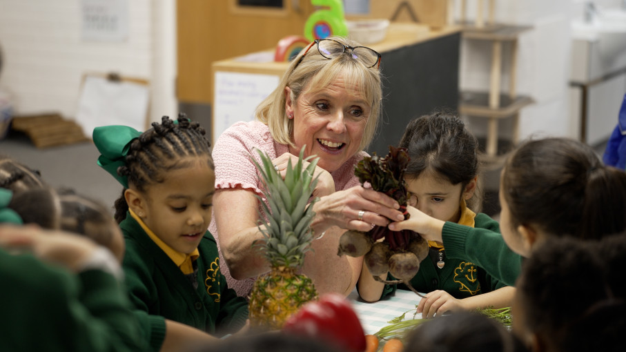 Maria Dunbar, CEO of Leiths Education is with primary school children, showing them a pineapple and beetroot.