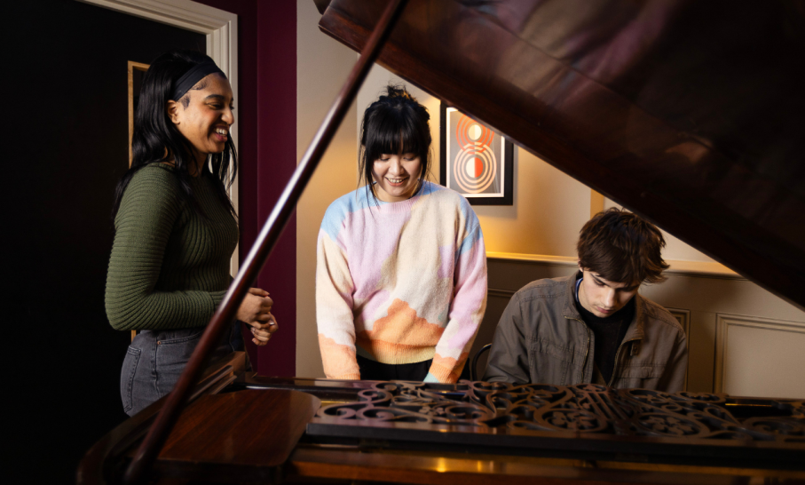 Three students at a piano 