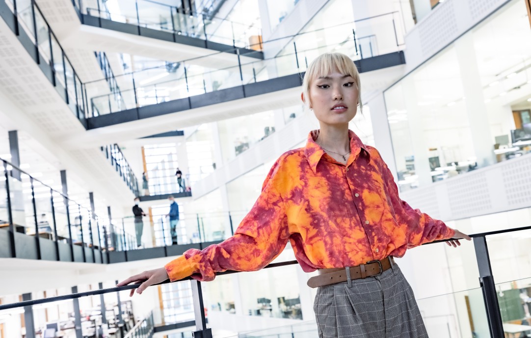 Asian student wearing colourful shirt posing on landing