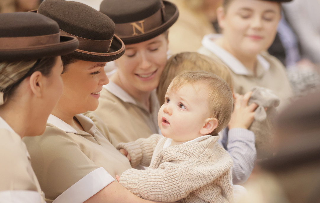 Norland nannies in brown hats, one holding a baby