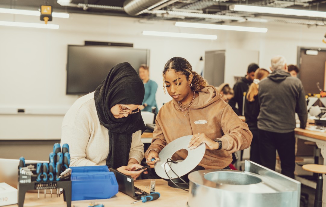Two students in a workshop using tools