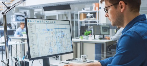 Engineer Working with CAD Software on Desktop Computer, Screen Shows Technical Drafts and Drawings. In the Background Engineering Facility Specialising on Industrial Design