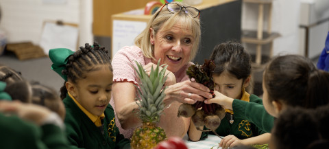 Maria Dunbar, CEO of Leiths Education is with primary school children, showing them a pineapple and beetroot.
