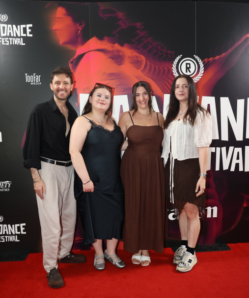 Young people standing on red carpet in front of festival poster