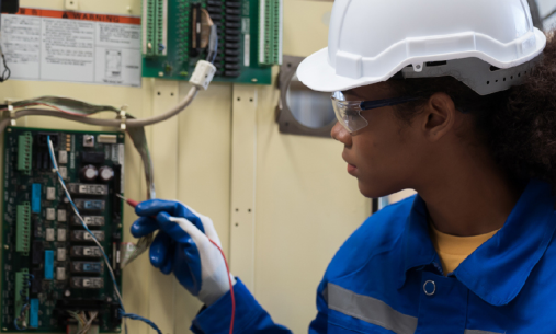 Engineer testing wiring inside an industrial electrical control cabinet.