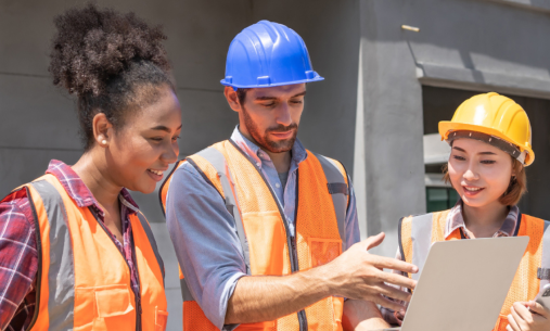 Construction team reviewing project information on a laptop at a worksite.