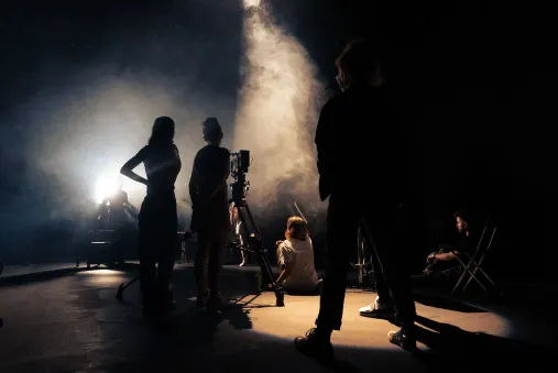 silhouettes of people filming in a dark, smoky room