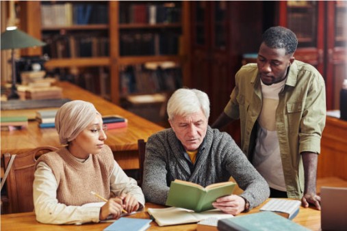 Three people sitting in a library reading