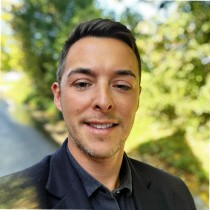Photograph of Oli Sussat, Chief Technology and Information Officer at The Harding Hub, standing against a background of greenery.